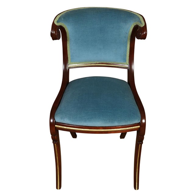 A Regency style mahogany side chair newly reupholstered in blue velvet, showcasing graceful neoclassical lines and finely...