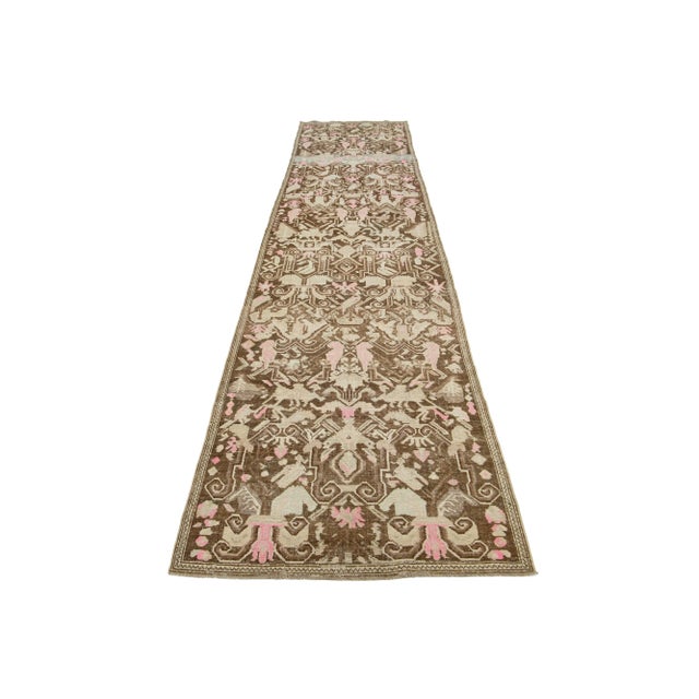 This is a beautiful Antique Karabagh hand-knotted wool runner with a brown-colored field. The rug showcases accents of...