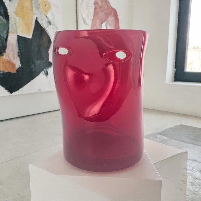 A sculptural hand-blown art glass vase rendered in saturated ruby red, featuring a series of evenly spaced pinched dimples...
