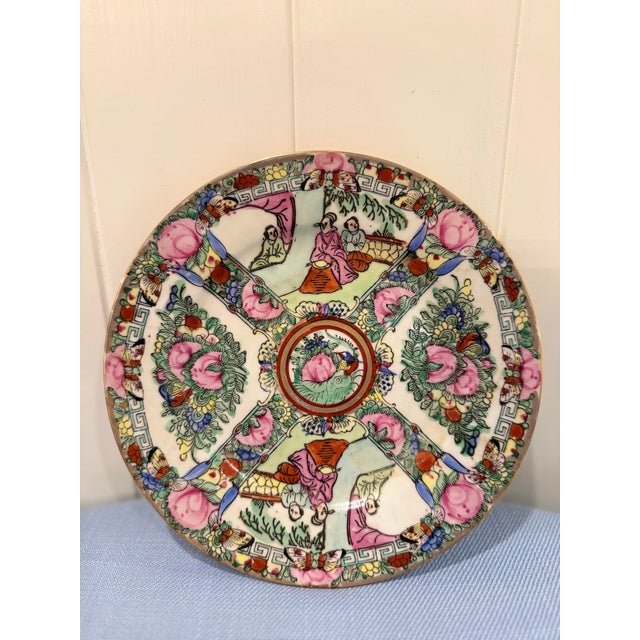 A vibrant vintage Japanese porcelain plate featuring a richly detailed Famille Rose-style design with florals, medallions,...