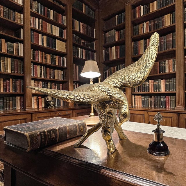 A large-scale vintage brass eagle sculpture depicting an American eagle descending onto a branch with wings fully...