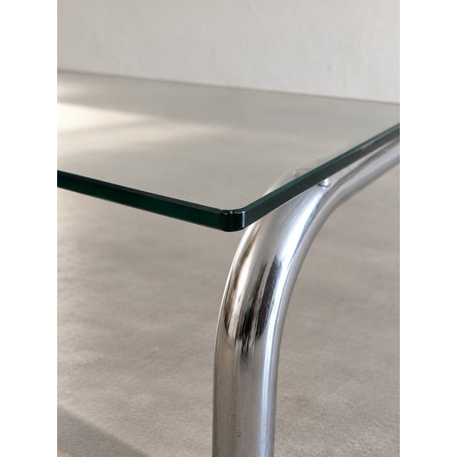 This coffee table combines a rectangular top with gently rounded corners and a single-piece tubular base in chromed metal....