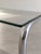 This coffee table combines a rectangular top with gently rounded corners and a single-piece tubular base in chromed metal....