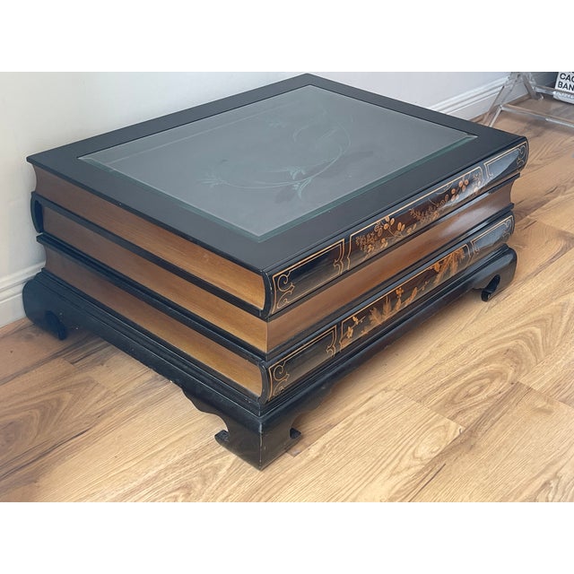 Maitland Smith style book coffee table with there drawers and cut glass top. Black lacquer and gold finish.