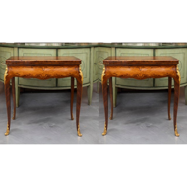 This is a classic pair of late 19th century mahogany and king wood Louis XV style inlaid game tables with the top opening...
