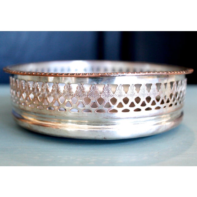 An early 20th century pierced fretwork gallery silver wine coaster with a turned wooden insert. Attractive patina with...