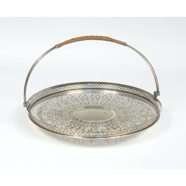 Apollo Sheffield pierced silver plate serving dish with swivel handle. The top of handle is wrapped in rattan. The foot is...