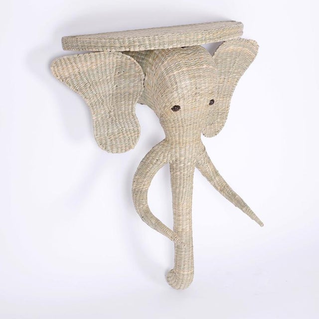 Whimsical pair of elephant head consoles crafted with a sturdy metal frame wrapped with reed.