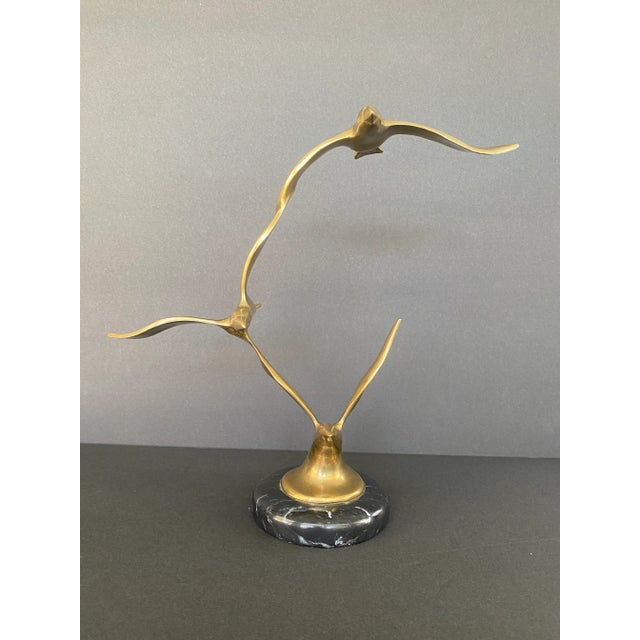 Mid-century modern three birds in flight brass sculpture on a round black marble base in the style of Curtis Jere.