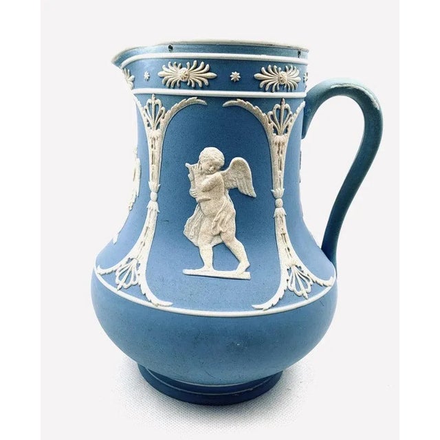 Dudson neo-classical pitcher in blue Jasperware. Decorated with sprig molded accents and cherub scenes. The interior is...