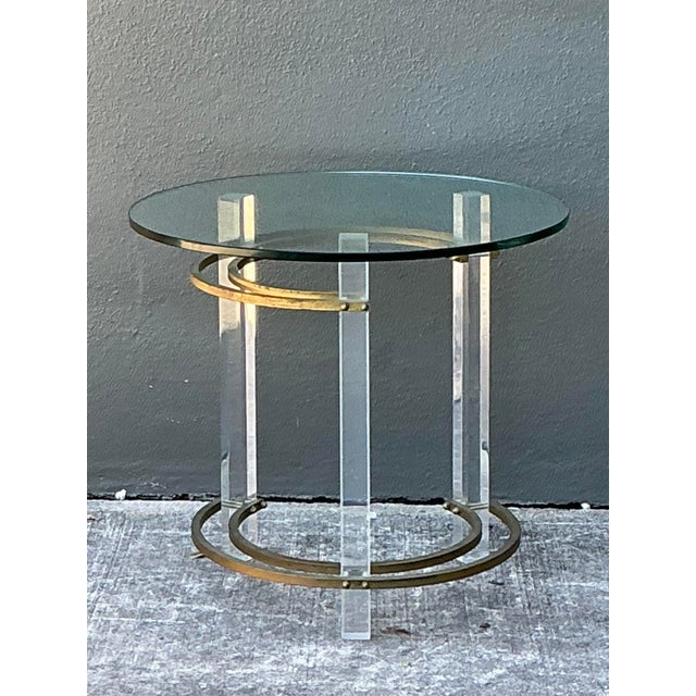 Capture the transparent glamour of the Hollywood Regency era with this striking side table in the manner of Charles Hollis...