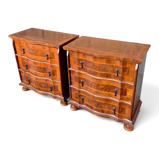 A pair of small three-drawer Italian chests. Each has a shaped serpentine front, burl walnut veneers, and brass teardrop...