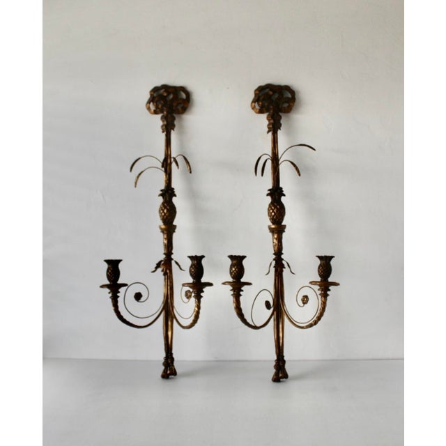 A dramatic pair of vintage French Regency-style pineapple and bow-tassel iron and carved wood wall candle sconces...