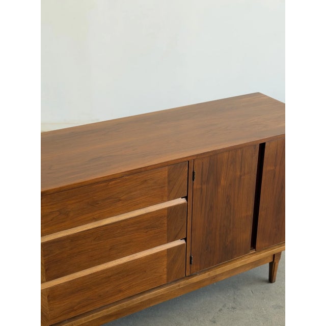 W54 D18.75 H31 This restored mid century credenza crafted from walnut offers practical storage through different concealed...