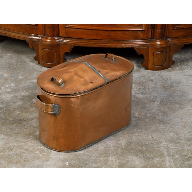 A large English copper braising pan from the mid 20th century, with lateral and top handles and weathered patina. Created...