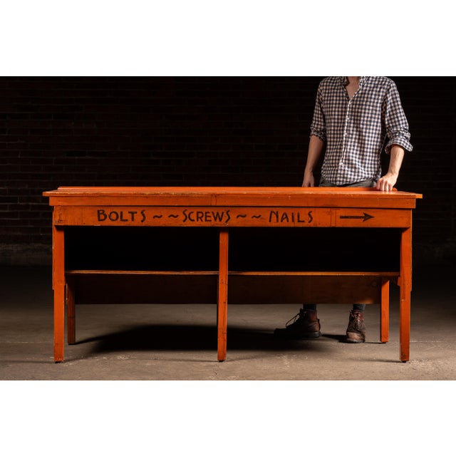Industrial painted pine hardware store counter or merchant's workbench featuring a plank top with rounded front corners...