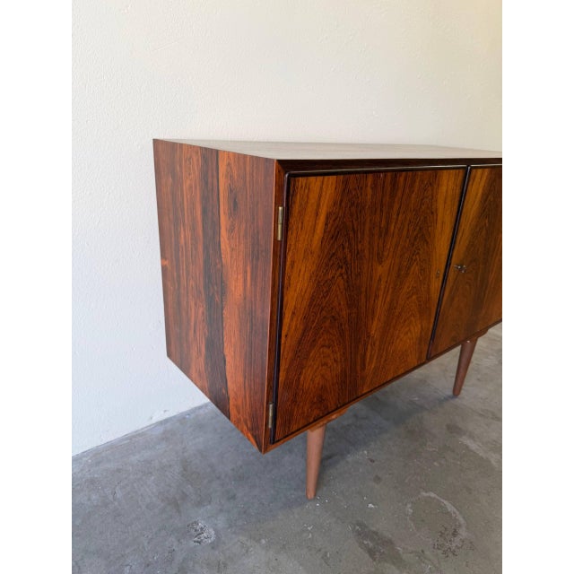 This Mid-Century Modern rosewood sideboard by Poul Hundevad exemplifies classic Danish craftsmanship and timeless...
