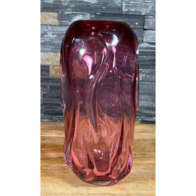 This 11-inch tall art glass vase has an elegant oval-cylindrical silhouette, gracefully narrowing at the smooth lip and...