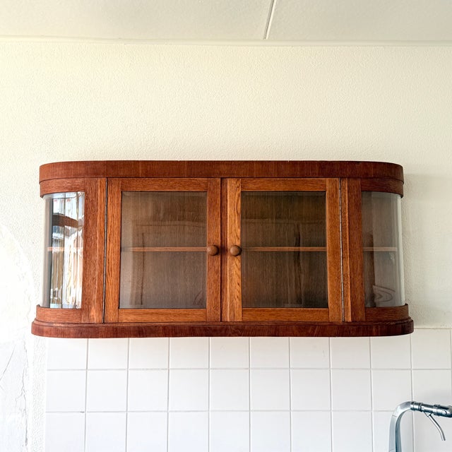 An impressive hanging display cabinet of German origin from the 1930s. The cabinet was handcrafted, with the curved,...