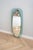 The oval mirror has a soft green glass frame and a bevel along the entire edge. It was made by the Italian company Fontana...