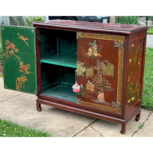 An artisan-crafted Qing dynasty style cabinetry adorned with carved figures and hand-painted landscapes against an oxblood...