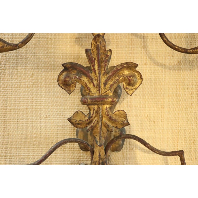An incredible pair of seven arm Italiante sconces. Hand made of cast iron and gilt tole, with turned wooden bobeches. A...