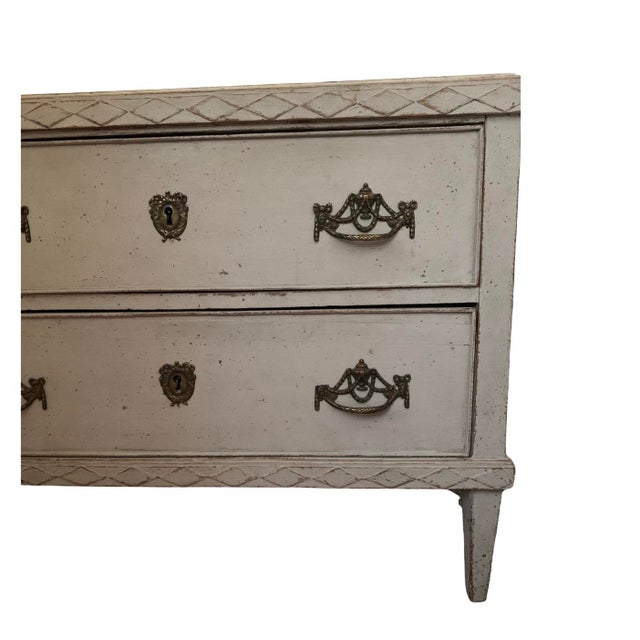 Later painted in light grey it has decorative diamond border detailing and two useful drawers with ornate metal handles...