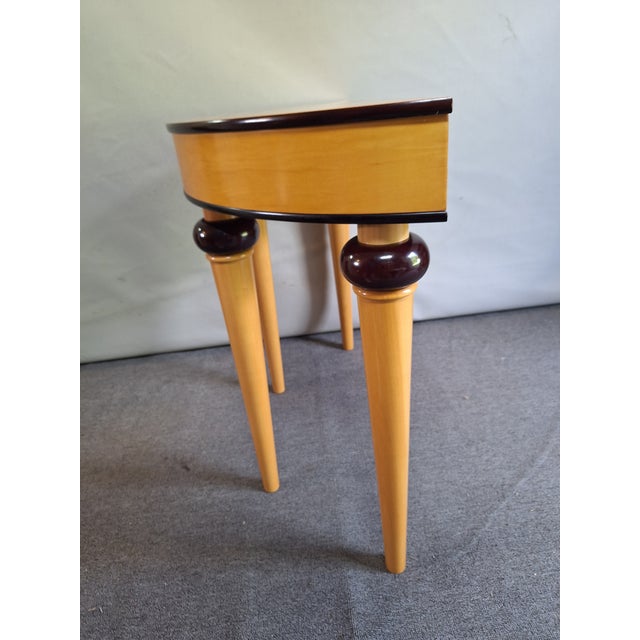 A vintage art deco style demilune table with mahogany trim flanking the frieze decorated with an inlaid diamond motif. The...