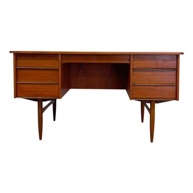 This mid-century modern teak executive desk features a double-pedestal design supported by tapered, sculptured legs. The...