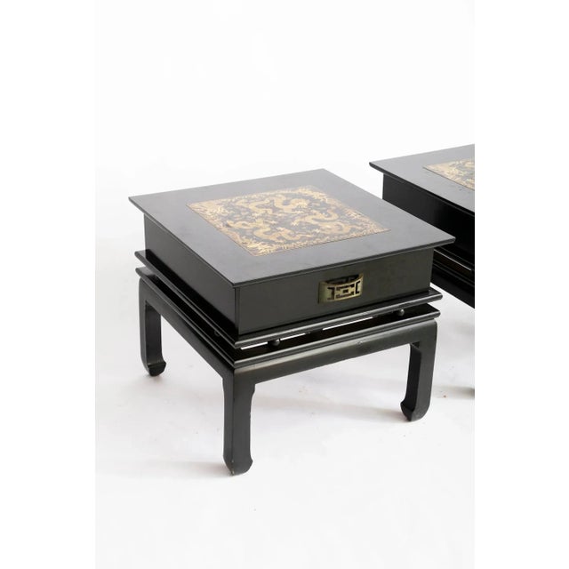 Elegant 1980s Chinoiserie bedside tables, each with a hand-lacquered black finish and engraved metal top depicting gold...