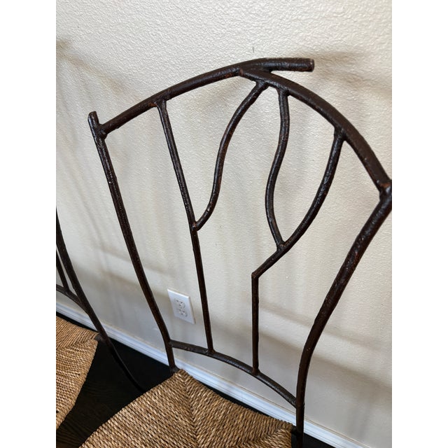 An attractive set of four dining chairs pairing slender, dark metal frames with warm natural woven seats. The chairs are...