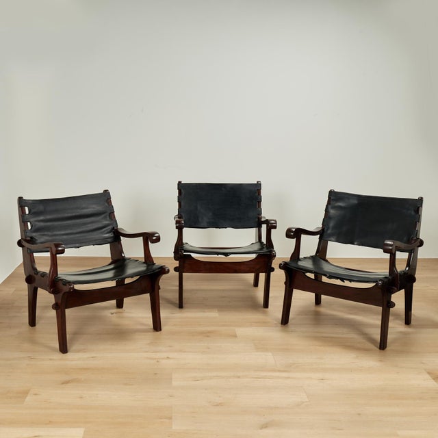 Chic set of three mid-century safari-style chairs crafted in richly grained rosewood, featuring sleek stylized frames,...