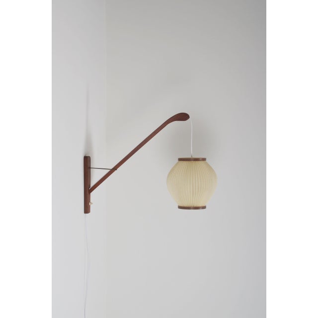 Danish wall lamp from the 1960s with a wooden arch in teak. The pearl shade lamp was designed by Lars Schiøler and...