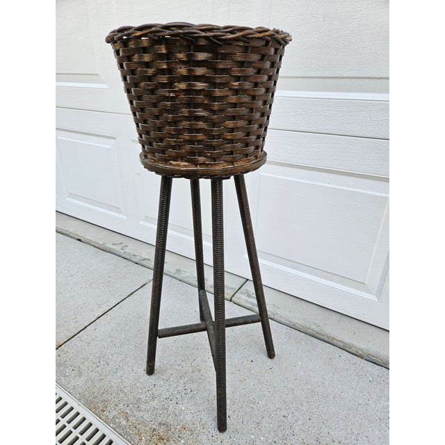 A classic wooden and wicker basket planter with spindle legs and an X based stretcher at the bottom. The interior...