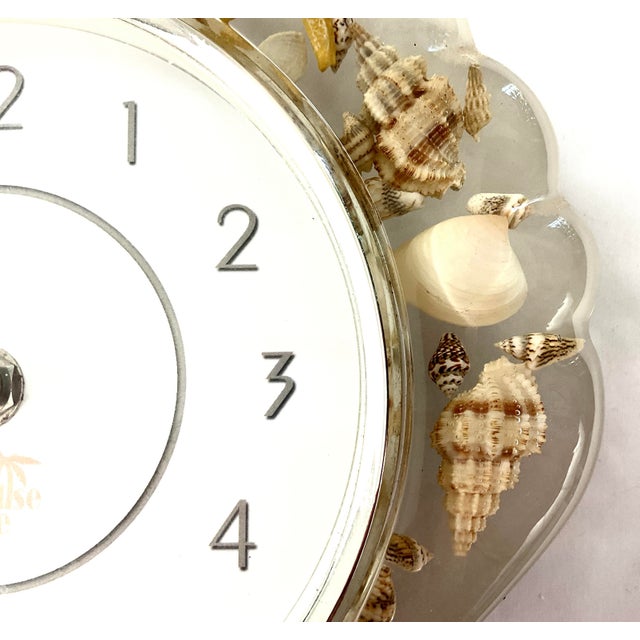Mid-century modern-coastal lucite wall clock in the shape of a shell Embedded throughout with tiny seashells Uses one AA...