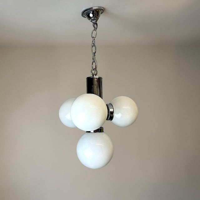 Striking vintage Space Age chandelier featuring four spherical white opaline glass globes arranged around a polished...