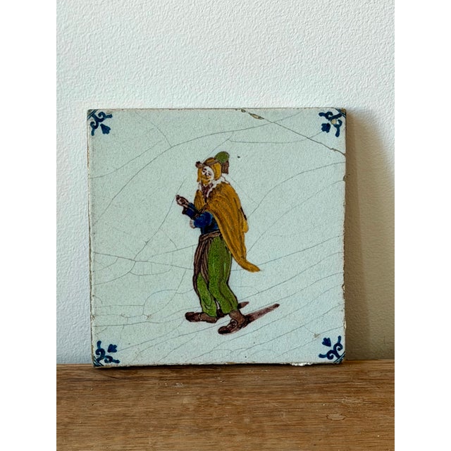 A charming pair of antique Delft-style ceramic tiles with hand-painted figural decoration and traditional corner...
