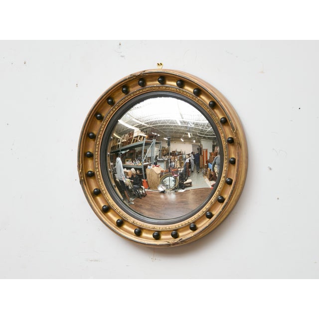 An English Regency giltwood convex mirror from the early 19th century, notable for its classic circular form and bold...