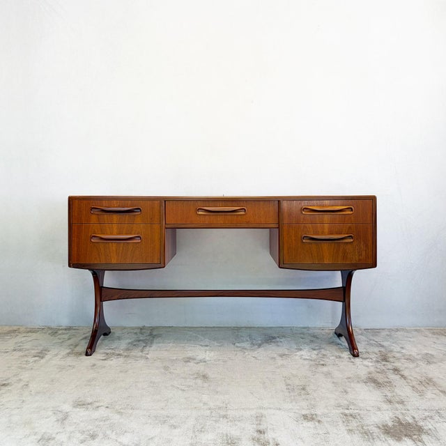 Constructed in teak, with two banks of drawers flanking a central kneehole, raised on the range's distinctive curved,...