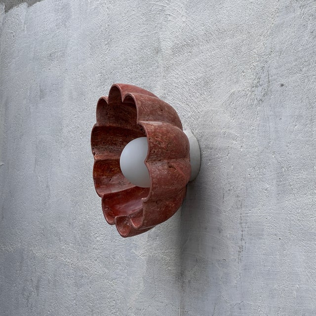 Hand-carved from solid red travertine, this lotus-inspired wall sconce doubles as sculpture and light. The petal-shaped...