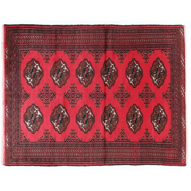 This vintage Turkmen rug exemplifies the artistry of Central Asian weaving traditions. The rich red background is...