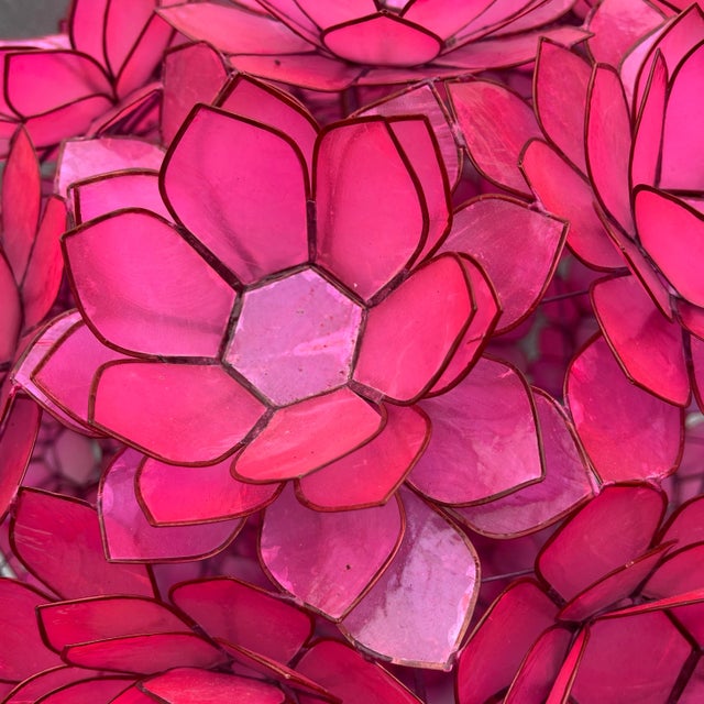 A stunning Worlds Away “Venus” pink capiz shell chandelier featuring layered lotus-style petals that form a sculptural...