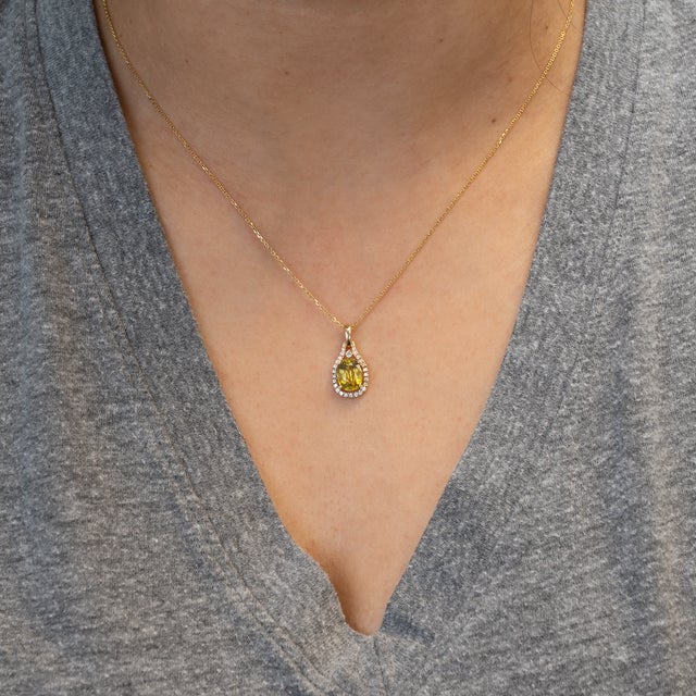 A natural sphene glows with green-gold brilliance and fire that rivals a diamond's, set within a halo of earth-mined...