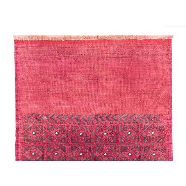 A bold vintage mid-20th century Turkish Kilim runner with a repeated diamond pattern set against a crimson background with...