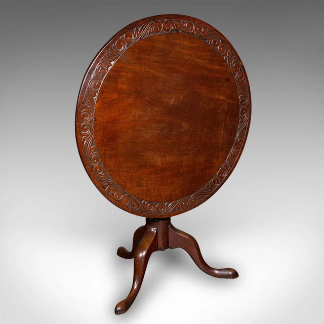 This is an antique display table. An English, walnut tilt-top hallway centre table, dating to the Georgian period and...