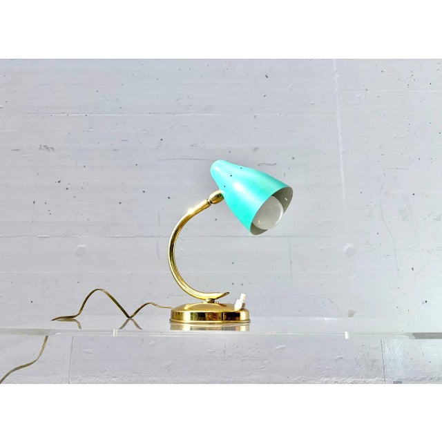 This distinctive table lamp impresses with its elegant, organically curved design, combining classic mid-century...