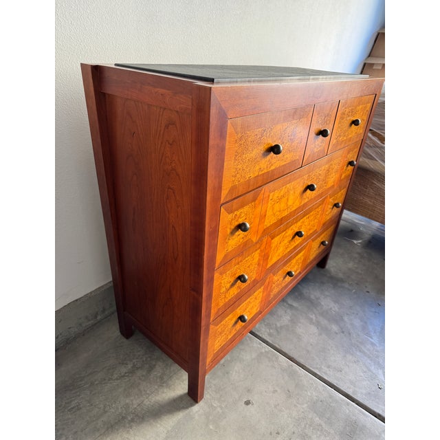 A beautifully crafted vintage chest by Baker Furniture, featuring dramatic book-matched burl wood drawer fronts, a warm...