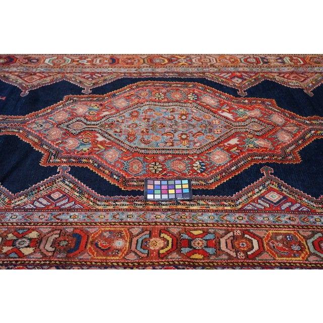 The stretched red and light teal geometric medallion features a peacock (or rooster) at each arrowhead finial, with bits...