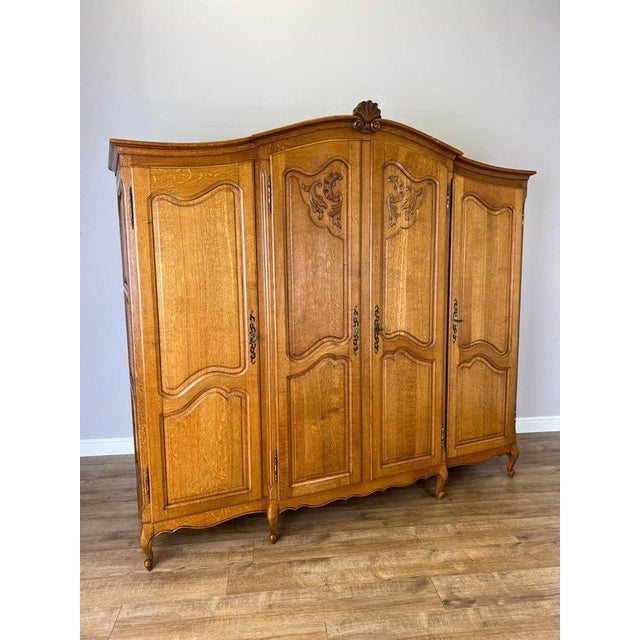 An elegant Vintage French Louis wardrobe crafted in oak, featuring an impressive four-door form, gracefully shaped upper...