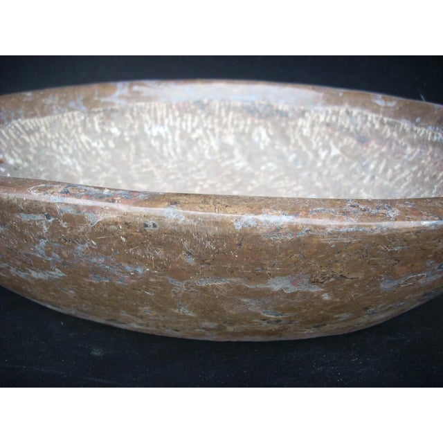 a solid block of stone carved into a bowl featuring a polished Ammonite fossil on the rim; from the Sahara desert in...